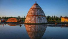 a large wooden structure sitting on top of a body of water next to a forest