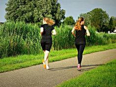 two women running down a path in the grass, one wearing black and the other with pink shoes