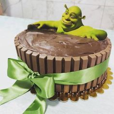 there is a chocolate cake with a green ribbon around it and a toy shrawn on top