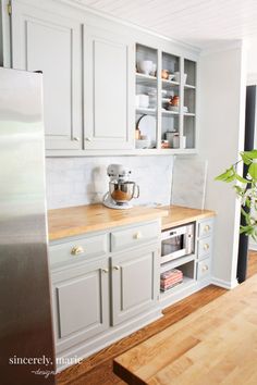 a kitchen with white cabinets and wood counter tops, along with a stainless steel refrigerator