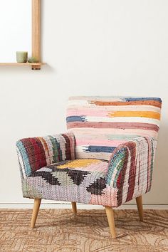 a multicolored chair sitting on top of a rug next to a wooden frame