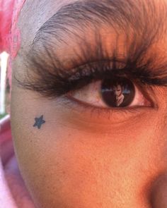 a close up of a person's eye with a small tattoo on their forehead