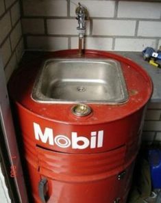 a red metal sink sitting next to a brick wall