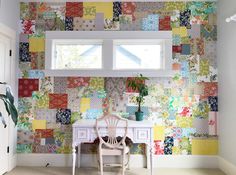 a chair sitting in front of a window next to a wall covered in patchwork