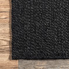 a black rug on top of a wooden floor next to a wood planked wall