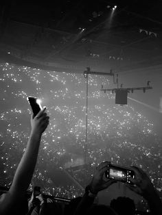 people taking pictures with their cell phones in front of an audience at a concert or show