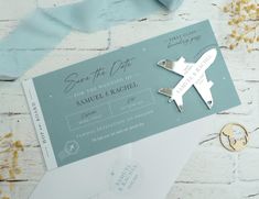 an airplane themed wedding save the date card and envelope with ribbon tied around it on a white brick wall