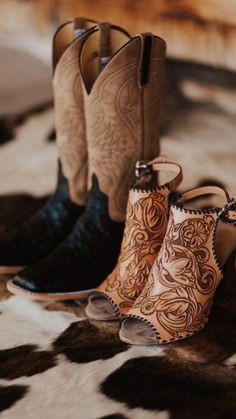 two pairs of cowboy boots sitting on top of a cow print rug