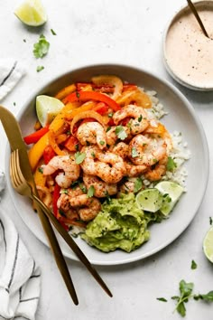 a white plate topped with shrimp and rice next to a bowl of salsa, cilantro