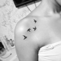 a woman's shoulder with three birds flying in the air on her left arm