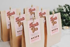 small thank you bags with pink and gold foil on them are hanging from clothes pins