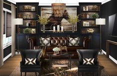 the living room is decorated in black and gold tones with leather furniture, bookshelves, and chandelier