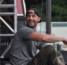 a man sitting on the ground with his arms spread out, wearing a hat and jeans