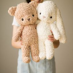 two stuffed animals are being held by a woman's hands in front of a wall