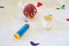 two spools of thread next to each other on a white surface with colorful beads