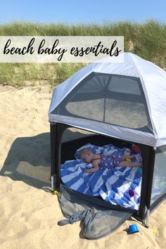 a baby laying in a tent on the beach with text overlay that reads, beach baby essentials