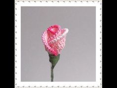 a pink crocheted rose is shown in the middle of a frame with white stitching