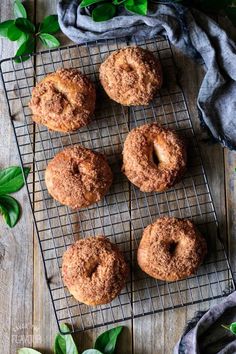 four doughnuts sitting on a cooling rack next to some leaves and a cloth