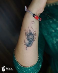 a woman's arm with a peacock tattoo on the left side of her arm