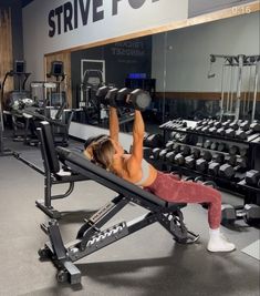 a woman is doing exercises on a bench in the gym with dumbbells behind her