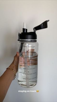 a person is holding a water bottle with the lid up and there are other items in it