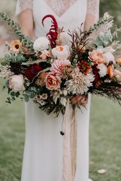 a woman holding a bouquet in her hands with flowers on the side and greenery