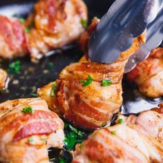 bacon wrapped chicken being cooked in a skillet with tongs and parsley on top