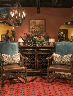 two chairs and a table in a room with chandeliers hanging from the ceiling