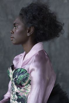 a woman with black hair wearing a pink shirt and tutu skirt looking off to the side