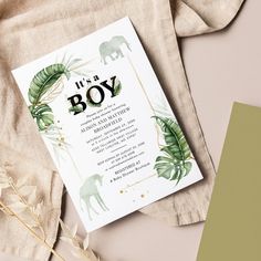 an elephant themed baby shower is displayed on a table with greenery and gold foil