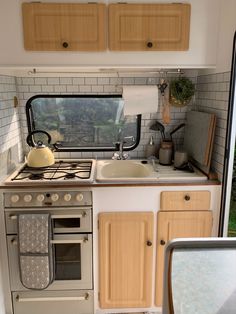 a kitchen with an oven, sink and stove top in a trailer or camper