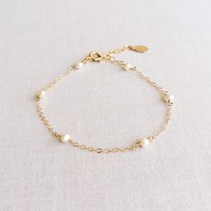 This is a 14k gold dainty pearl bracelet with adjustable chain in 14k or gold filled Dainty Pearl Charm Bracelet Adjustable, Elegant Pearl Charm Bracelet For Wedding, Elegant Pearl Bracelet With Extender For Gift, Elegant Pearl Bracelet With Extender As Gift, Delicate Pearl Gold Bracelet For Gift, Dainty Hypoallergenic Charm Bracelet For Weddings, Dainty Pearl Bracelets For Anniversary, Wedding Gold Bracelet With Pearl Drop, Wedding Gold Pearl Bracelet With Pearl Drop