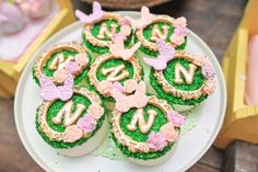 there are many decorated cookies on the plate and one is pink, green and gold