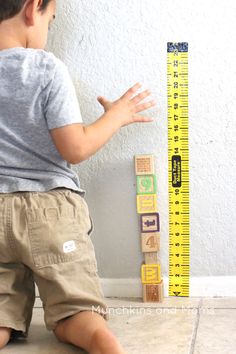 a little boy playing with wooden blocks and a measuring tape on the floor in front of him