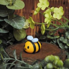 a yellow and black bee figurine sitting on top of a tree stump