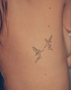 a small tattoo on the back of a woman's stomach, depicting two little tinkerbells