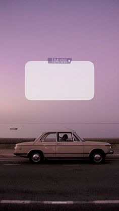 an old car is parked on the side of the road in front of a billboard