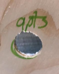 a hole in the side of a piece of paper with green writing on it that says apis