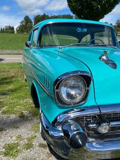 an old blue car is parked in the grass