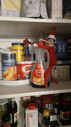 an elf is standing on top of a shelf in a pantry filled with food and condiments