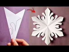 someone is making a snowflake out of paper and then cut it with scissors