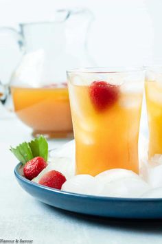 two glasses filled with ice and strawberries on a plate