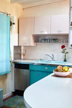 a bowl of fruit is sitting on the counter top in this small, clean kitchen