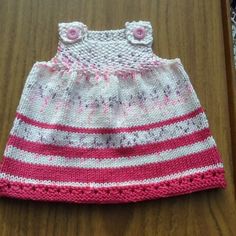 a pink and white knitted hat sitting on top of a wooden table