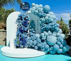 a blue and white display with balloons in the shape of trees, bushes and flowers