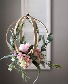 a flower arrangement hanging from a chandelier with greenery and flowers in it