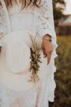 a woman holding a white hat with flowers on it