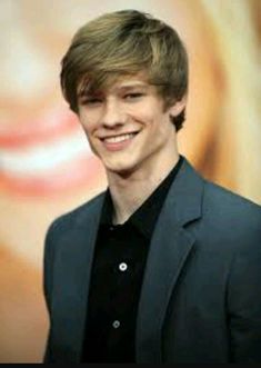 a young man in a suit smiling at the camera