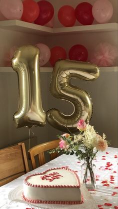 a table with a heart shaped cake and balloons