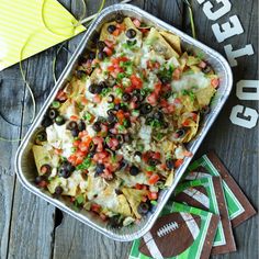 a casserole dish filled with black olives, peppers and cheese on top of a wooden table